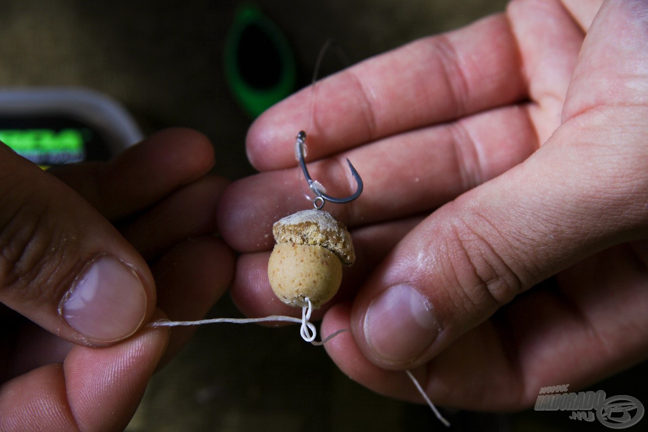 Ha ezzel megvagyunk, a csalit toljuk fel a forgóra, és egy csaliütközőt toljunk bele a pop-up bojliba, amire aztán a Bait Floss kilógó száraiból egy sima csomót kell kötni